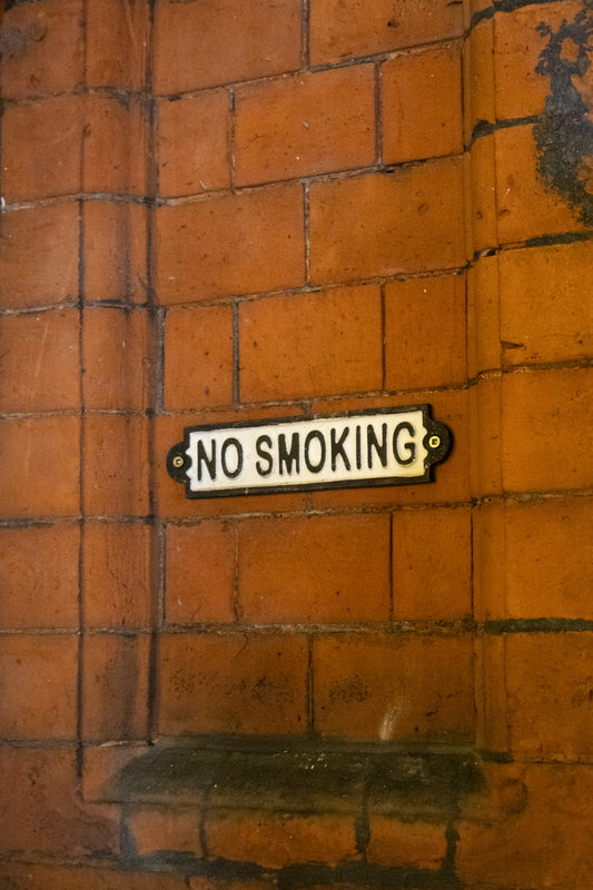 A white no smoking sign on brick wall