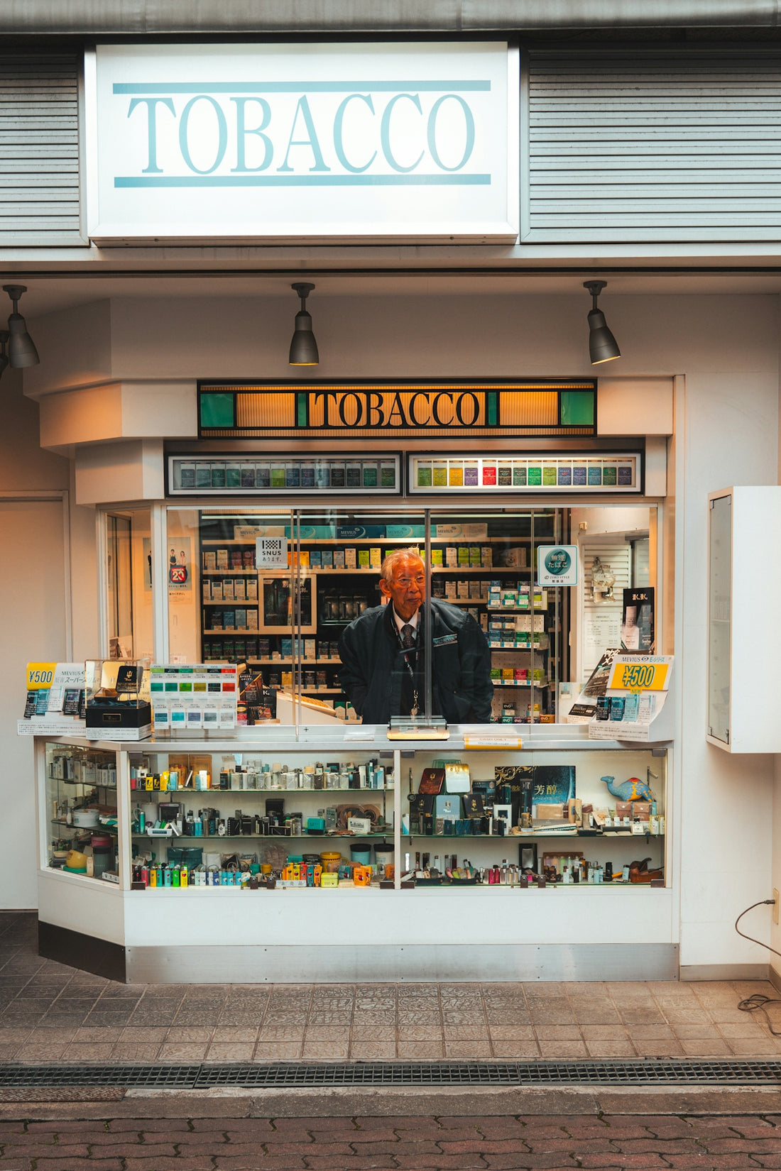 Elderly man stands inside a brightly lit tobacco shop